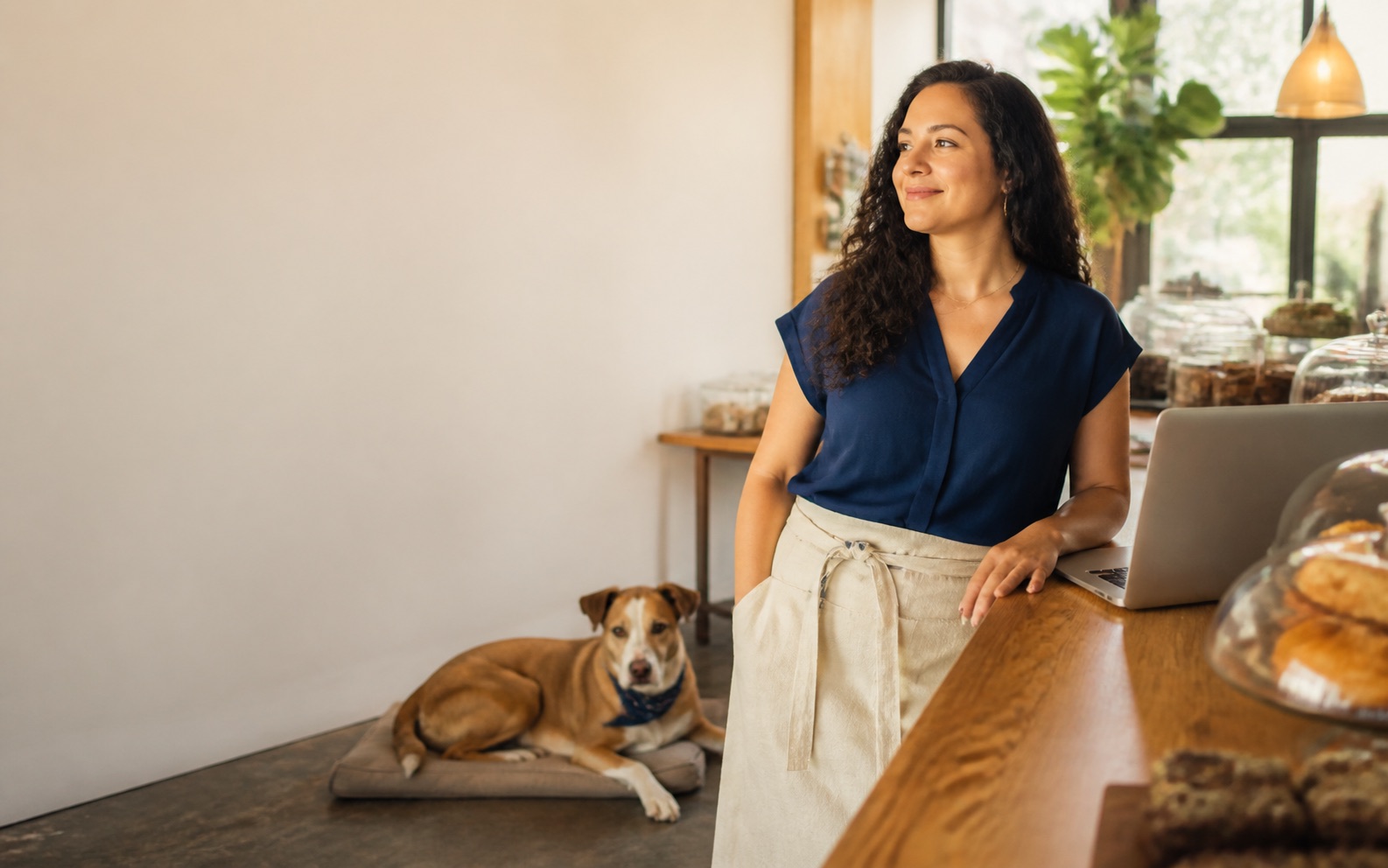 Local small-business owner with a laptop and rescue dog in her neighborhood café