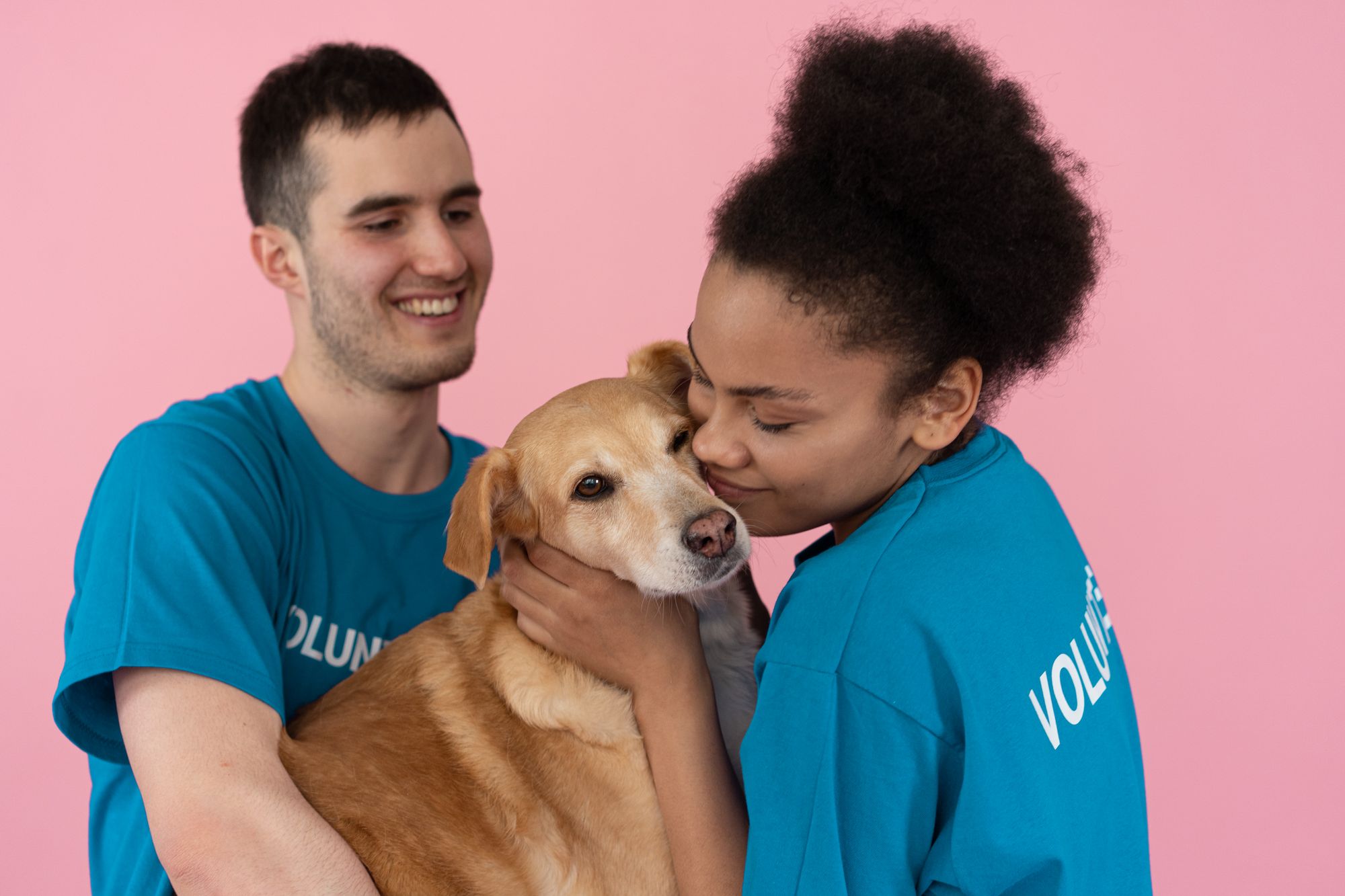 Two animal-welfare volunteers hugging a friendly rescue dog